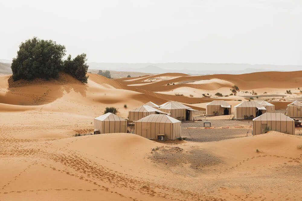 Luxury desert camp in Merzouga with traditional tents and stunning Sahara dunes at sunset