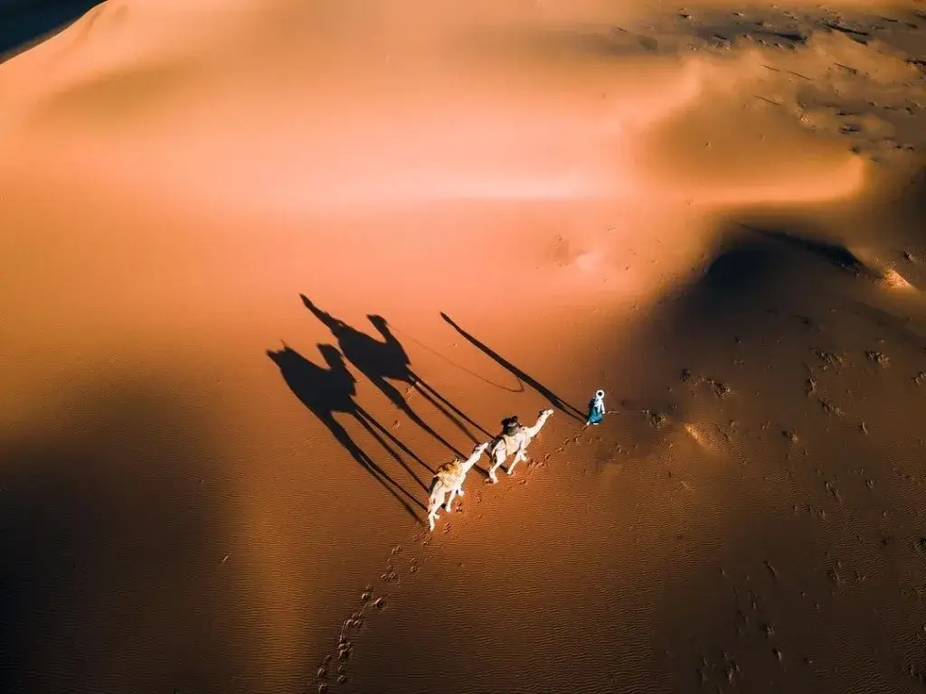 Escursione di 4 giorni da Marrakech a Merzouga, con vista sulle dune del deserto e viaggiatori a cavallo di cammelli.